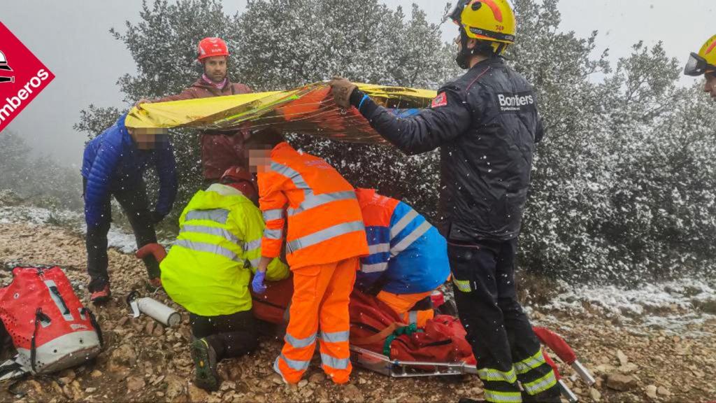 Los bomberos y sanitarios atienden a la accidentada en la montaña.