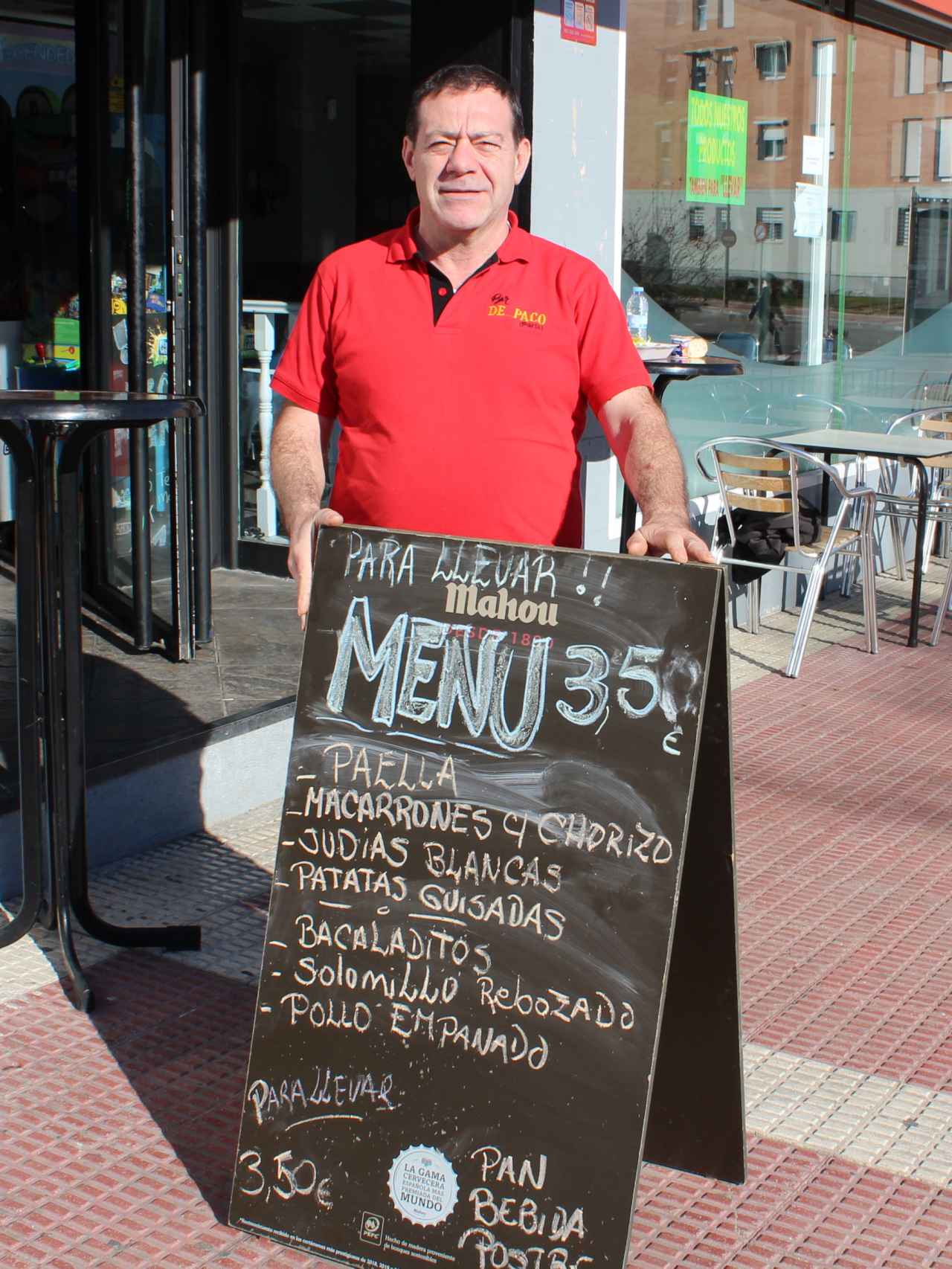 Paco, en la puerta de su bar, junto al cartel que anuncia el menú del día a 3,50 euros.