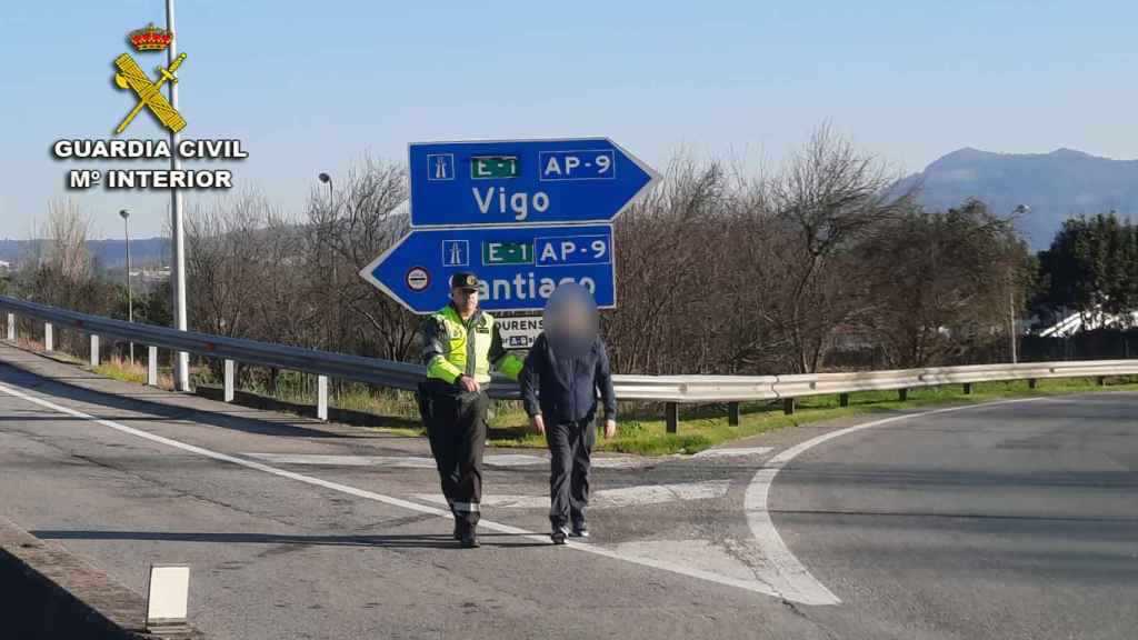 Un agente de la Guardia Civil ayuda al peatón en la AP-9.