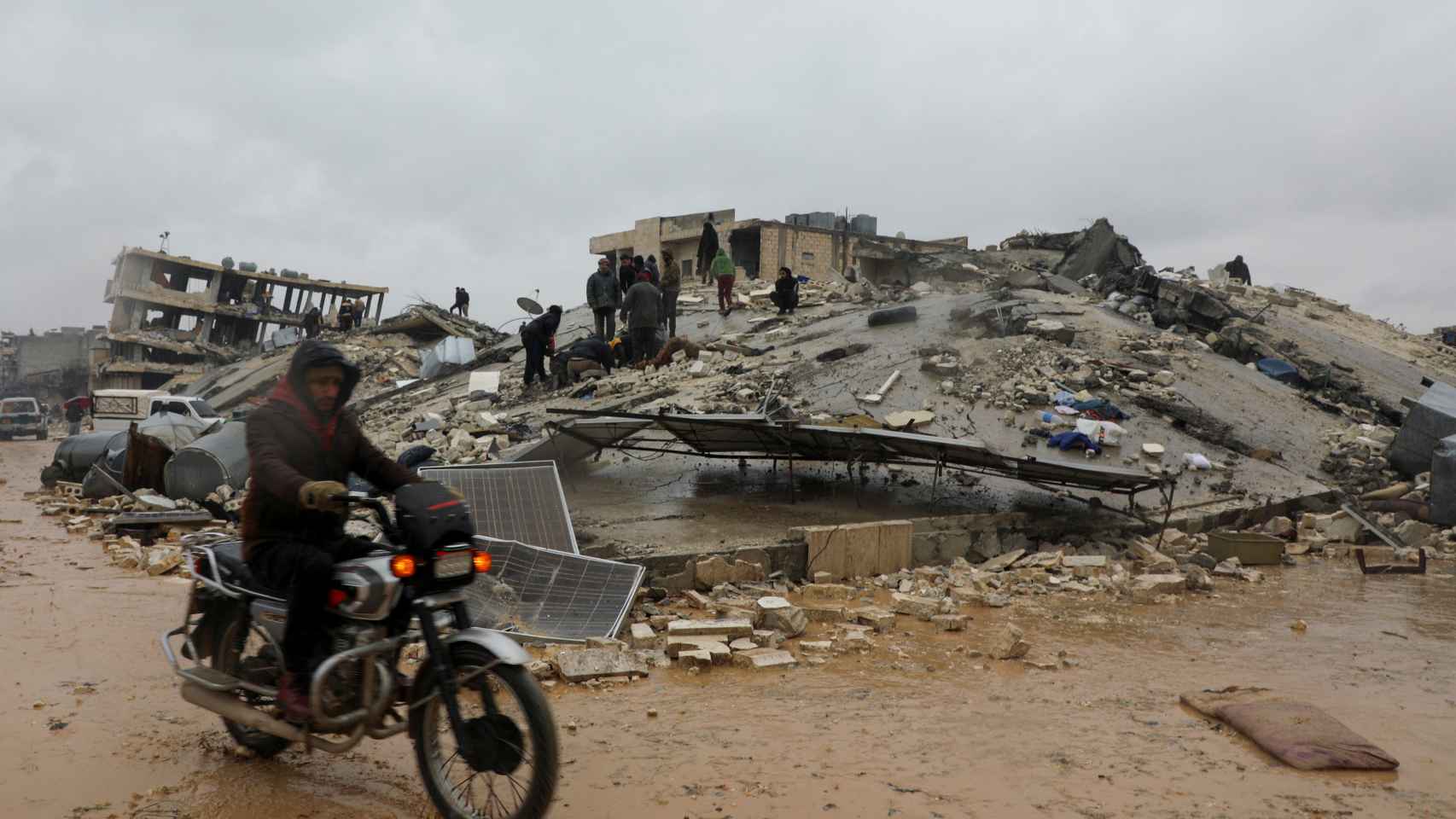 Personas buscan a supervivientes bajo los escombros en la ciudad rebelde de Jandaris (Siria).