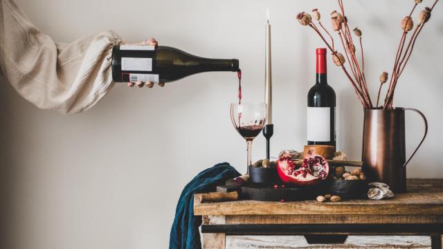 Una mujer, llenando una copa de vino.