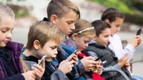 Niños 'pegados' a sus móviles en imagen de archivo.