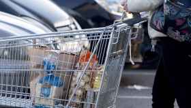 Imagen de archivo de una mujer saliendo de un supermercado con un carro de la compra.