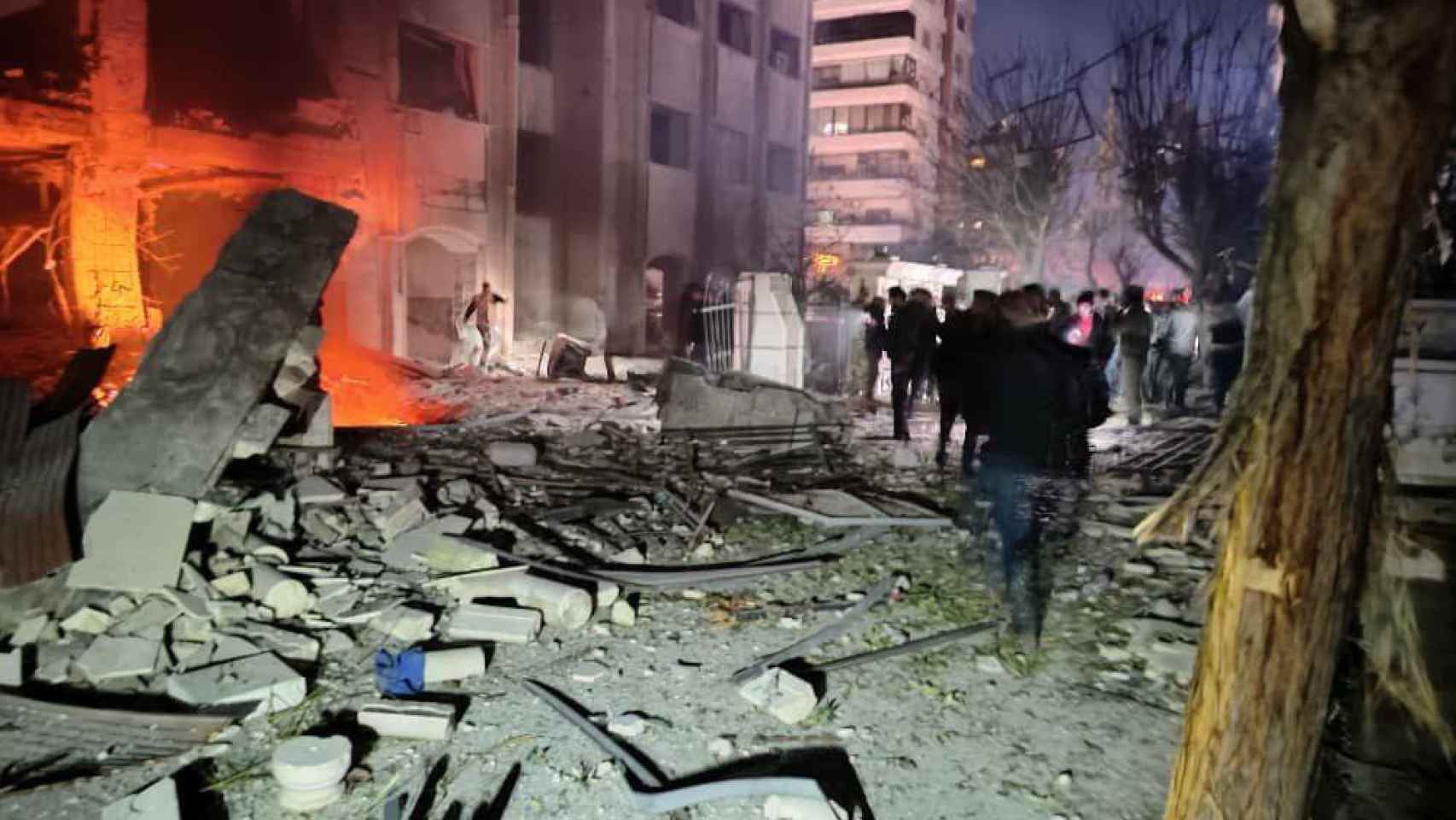 Un grupo de personas contemplan los daños en un complejo residencial, en Damasco.