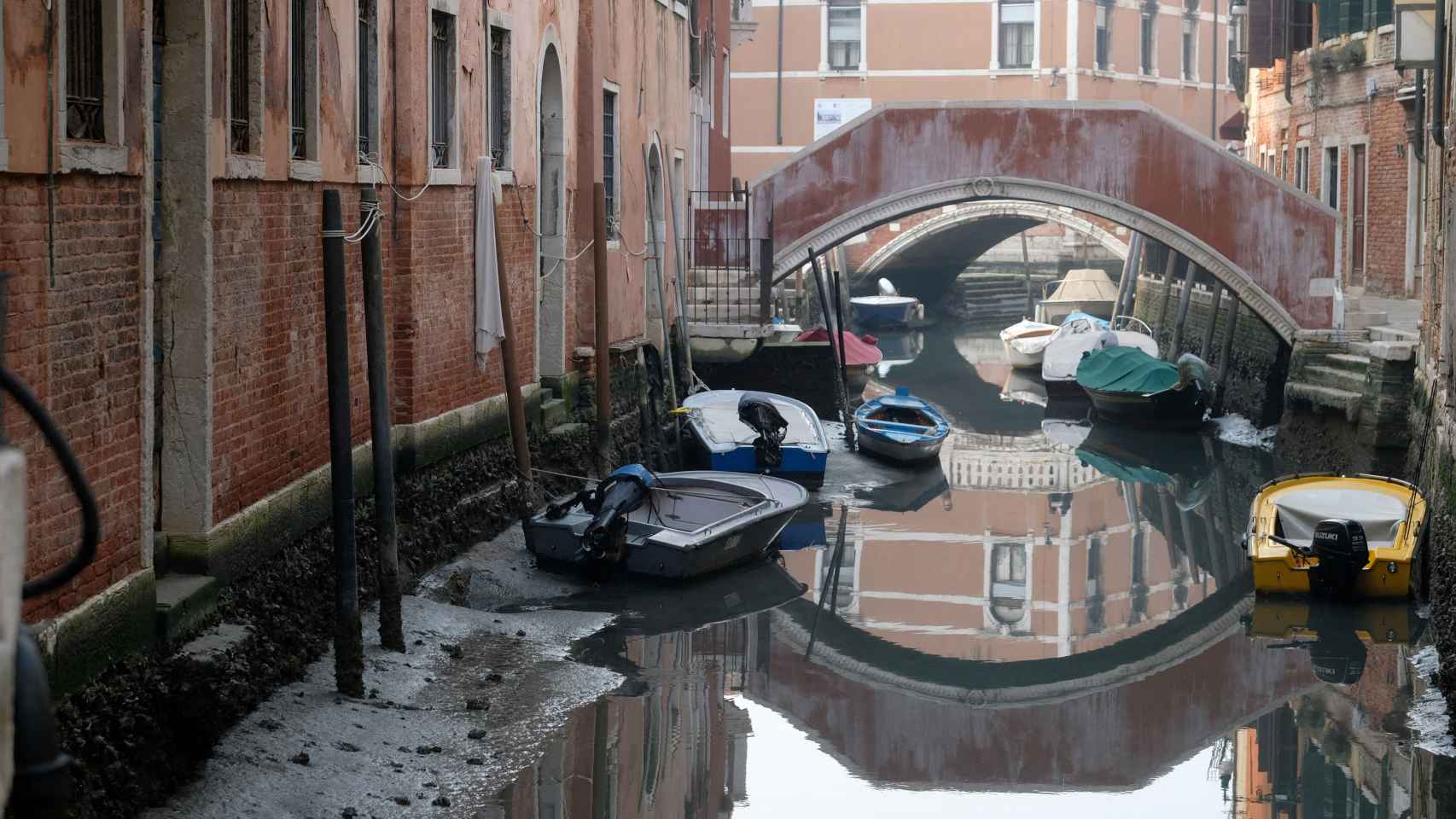 Barcos en un canal durante una fuerte bajamar en la laguna de Venecia