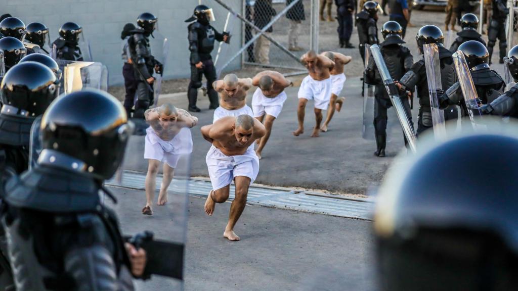 Los agentes penitenciarios observan a los pandilleros mientras son procesados a su llegada, en Tecoluca, El Salvador