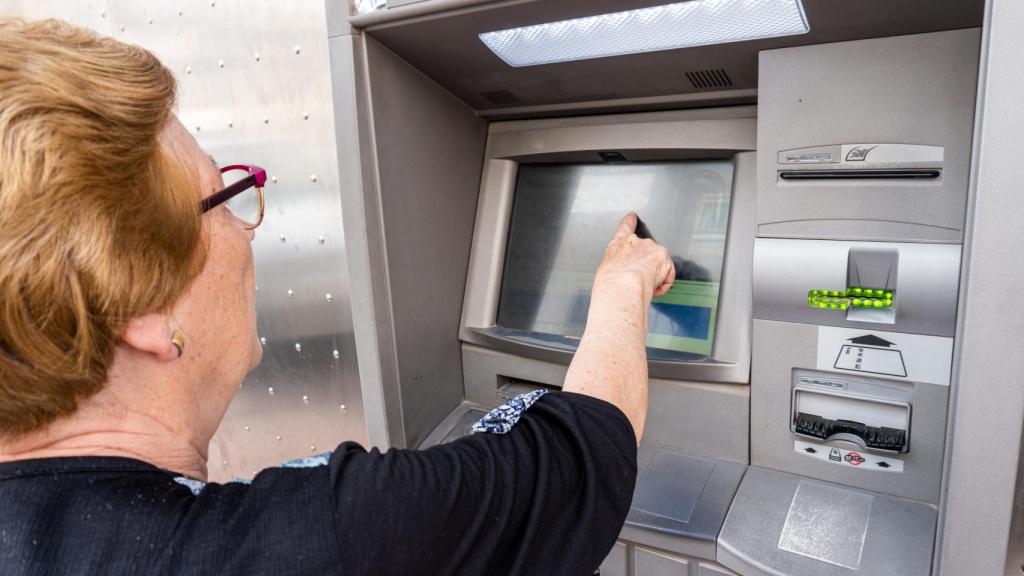 Una mujer anciana saca dinero de un cajero, en una imagen de archivo.