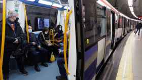 Varias personas con mascarilla dentro de un tren de Metro en la estación de Metro de Sol.