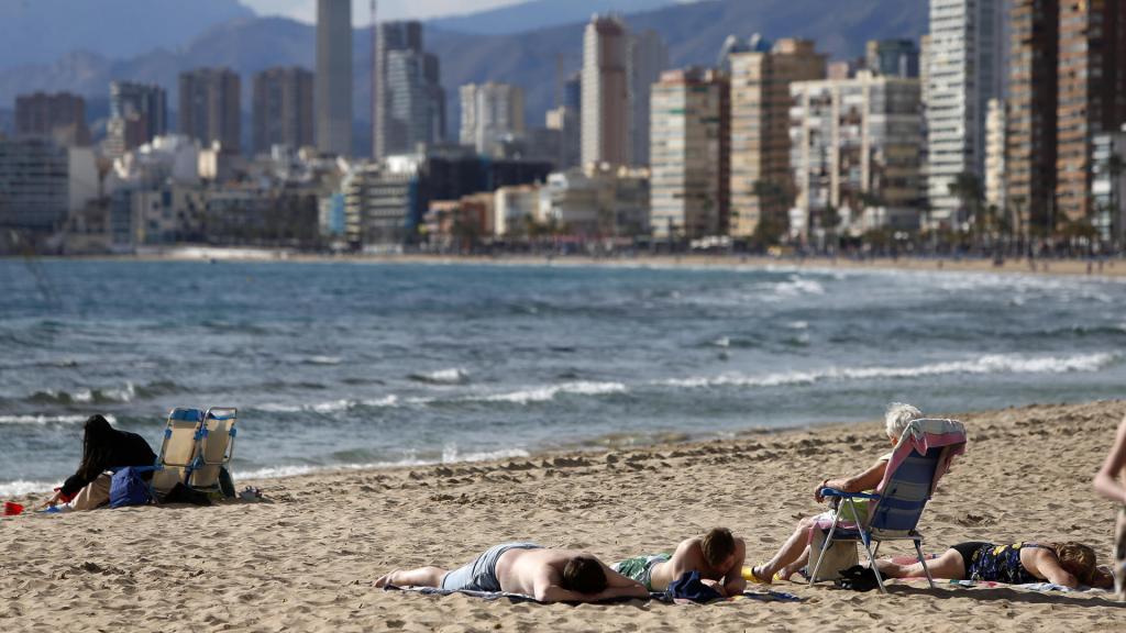 Varios turistas en una playa de Benidorm con el 'skyline' de fondo, este mes de febrero.