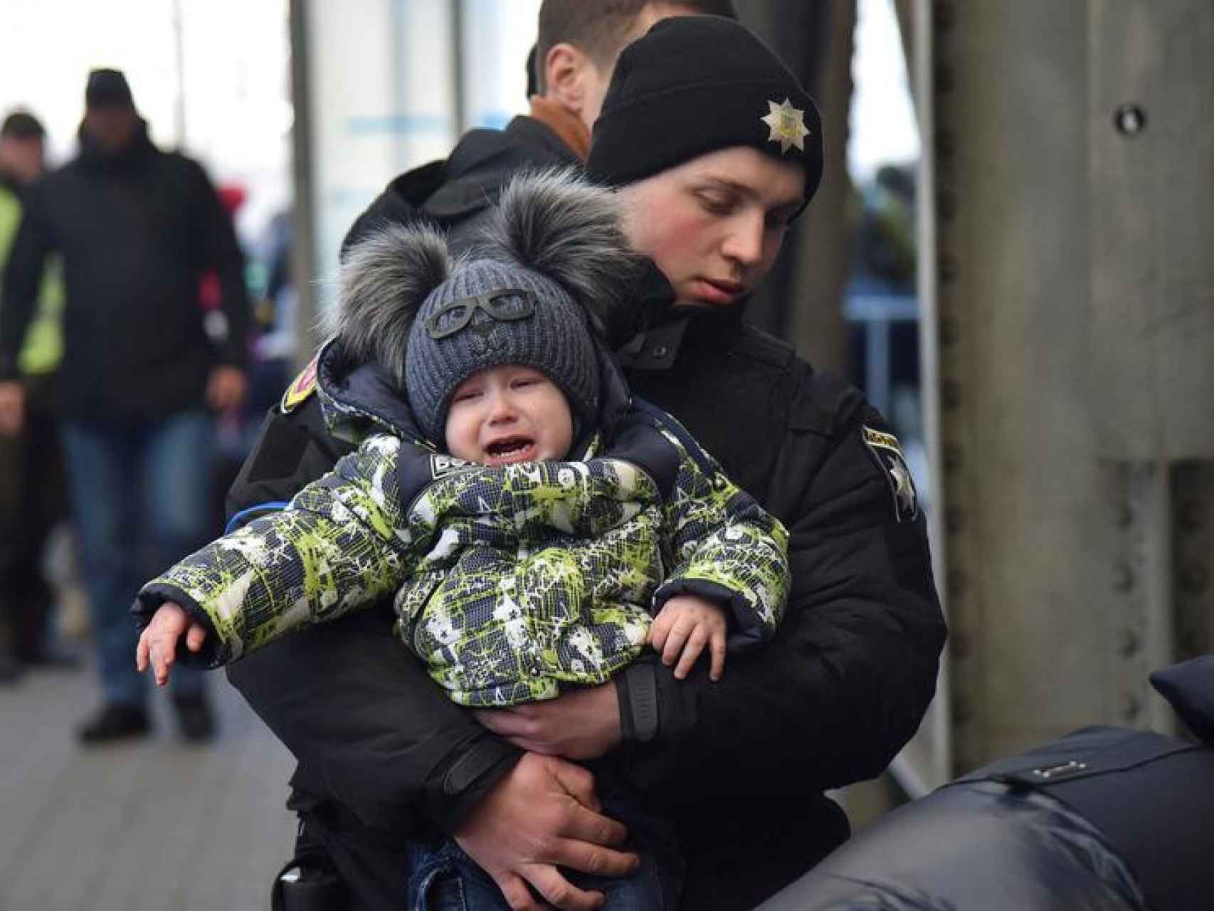 Un oficial de policía carga con a un niño que huye de la invasión rusa de Ucrania.