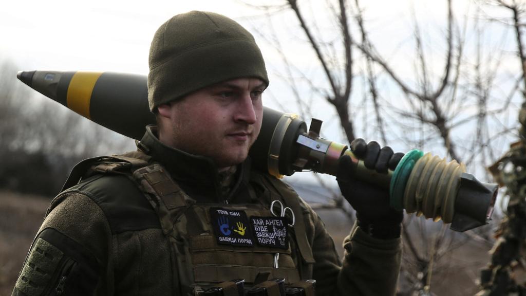 Un miembro del servicio ucraniano lleva un proyectil de mortero antes de disparar contra las tropas rusas en las afueras de la ciudad de Bakhmut .