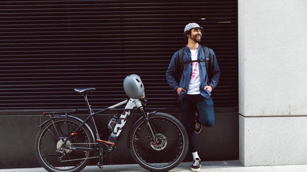 Un joven posa con su bicicleta eléctrica.