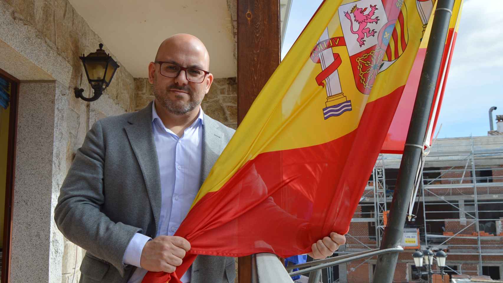 José Luis Labrador posa con la bandera de España en el Ayuntamiento de Manzanares El Real.