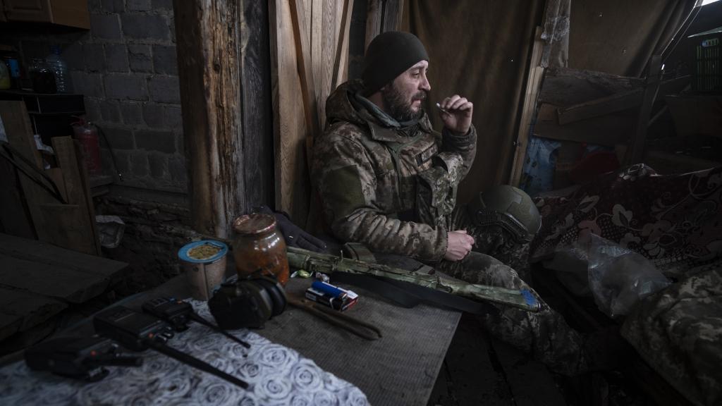 Un soldado ucraniano fuma un cigarrillo mientras está pendiente de las comunicaciones por radio en una trinchera, situada en un punto del frente de combate de Vuhledar (Donetsk).