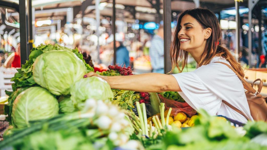 Una mujer joven seleccionando frutas y verduras.