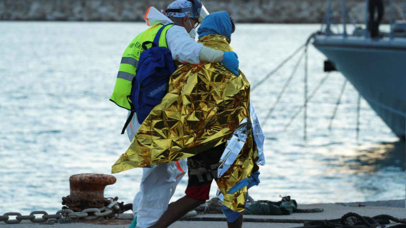 Un migrante rescatado de un naufragio en el Mediterráneo asistido por un miembro de la Cruz Roja a su llegada al puerto siciliano de Pozzallo.