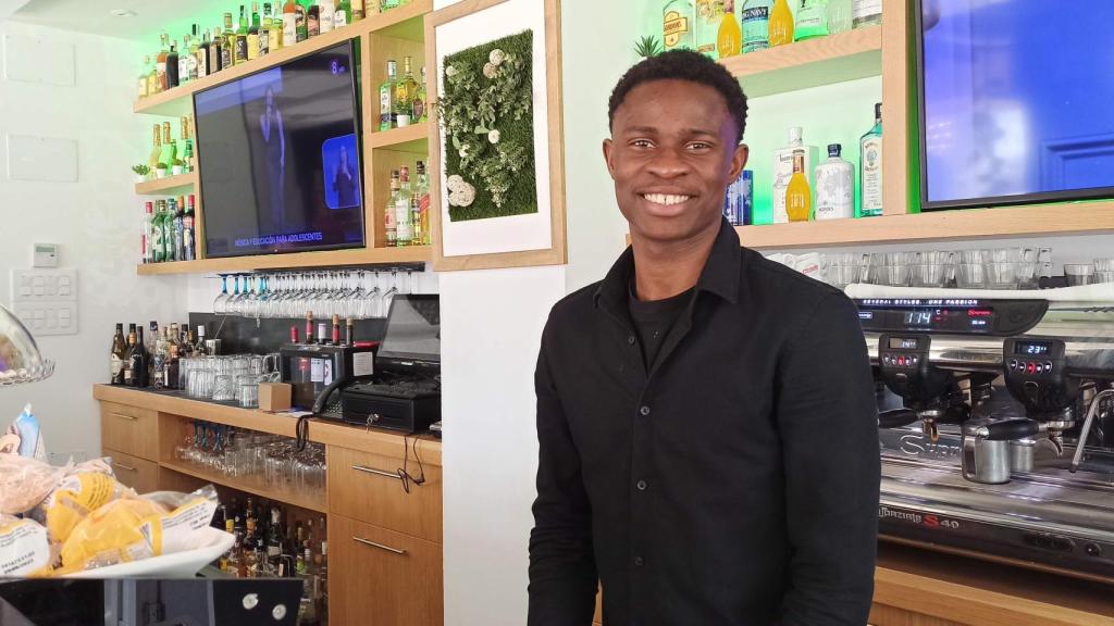 Abdoul sonríe tras la barra de la cafetería del hotel que le ha dado una oportunidad de salir adelante