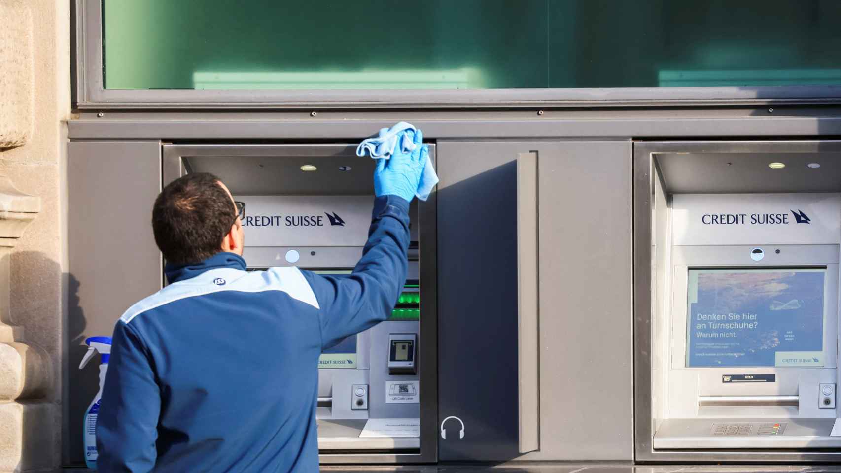 Un trabajador limpia un cajero de Credit Suisse la mañana del lunes 20 de marzo tras la compra de UBS.