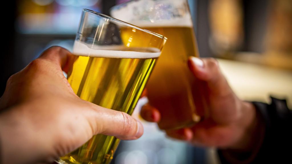 Dos jóvenes brindando tras beber un par de cervezas.