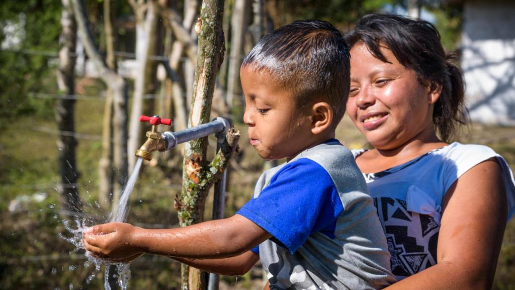 Un niño cogiendo agua de una fuente.