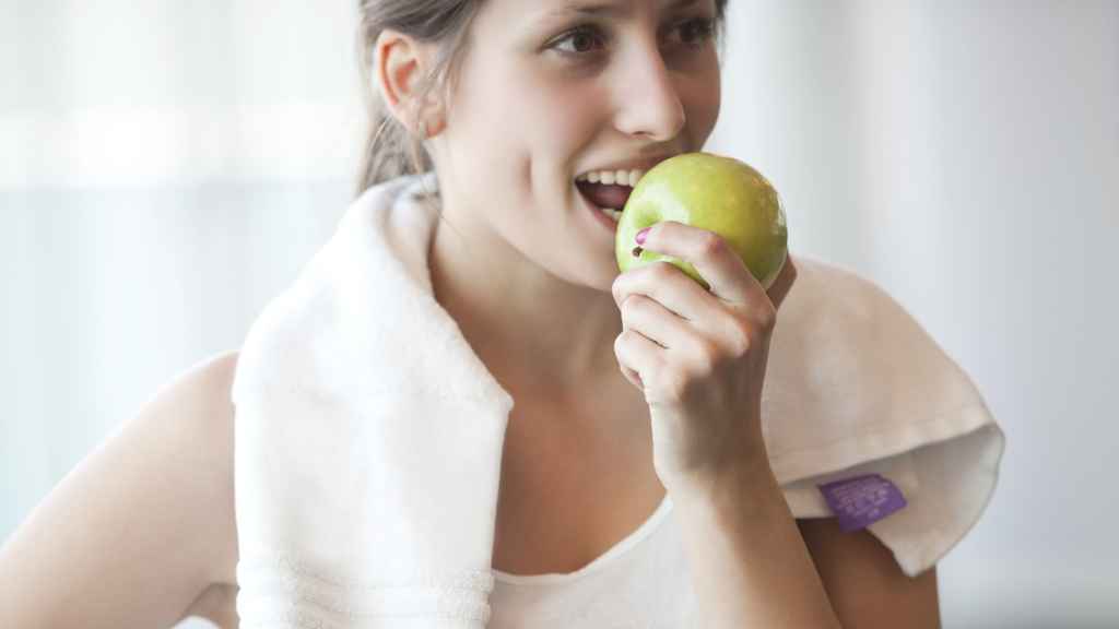 Mujer comiendo manzana en una ruptura de ejercicios. Fuente: iStock.