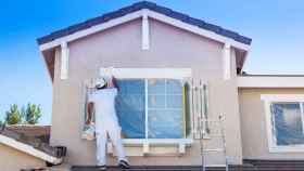 Un hombre pintando la fachada de una casa