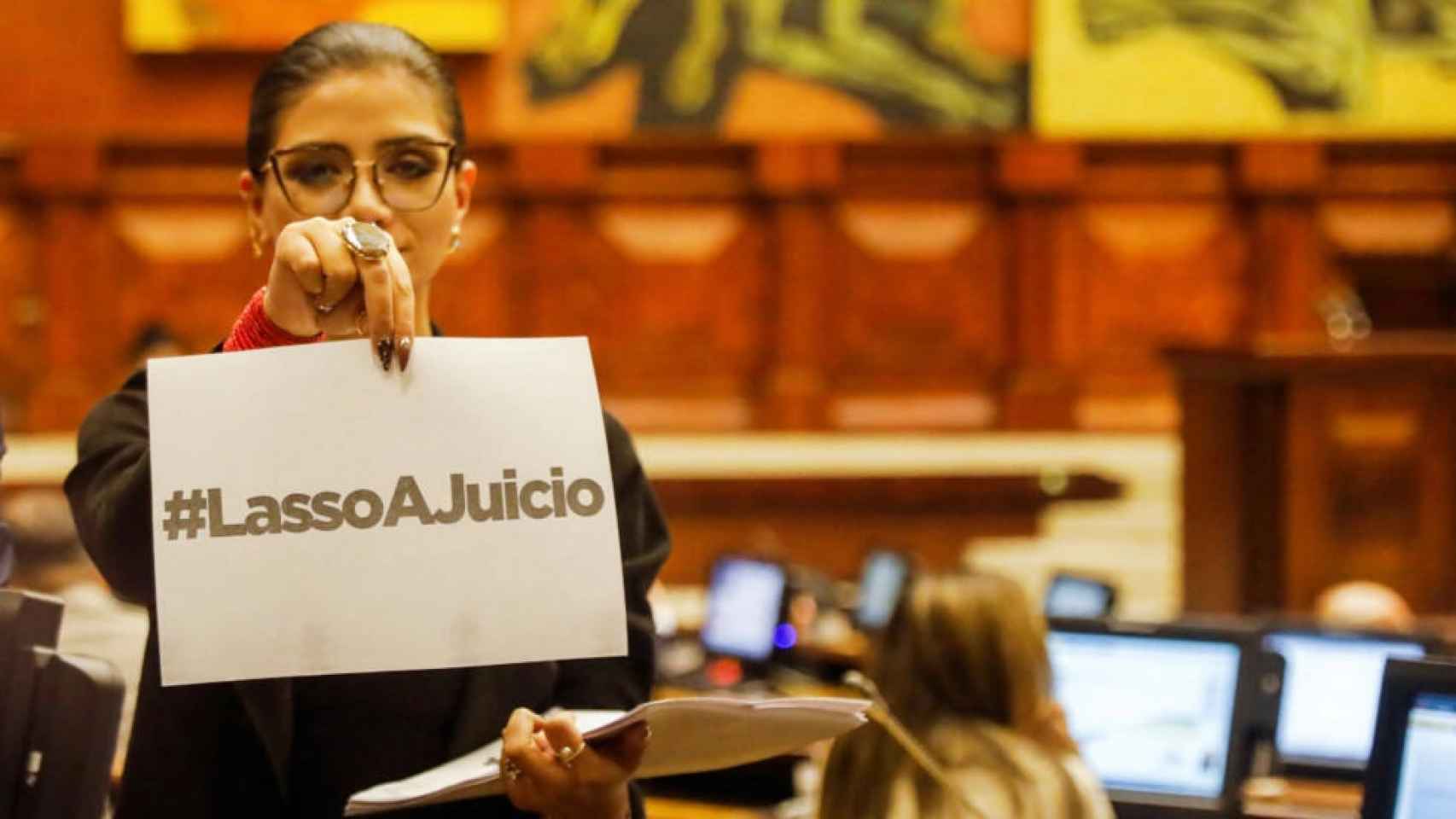 Una parlamentaria sostiene un cartel que dice Lasso a Juicio en el hemiciclo de la Asamblea Nacional.