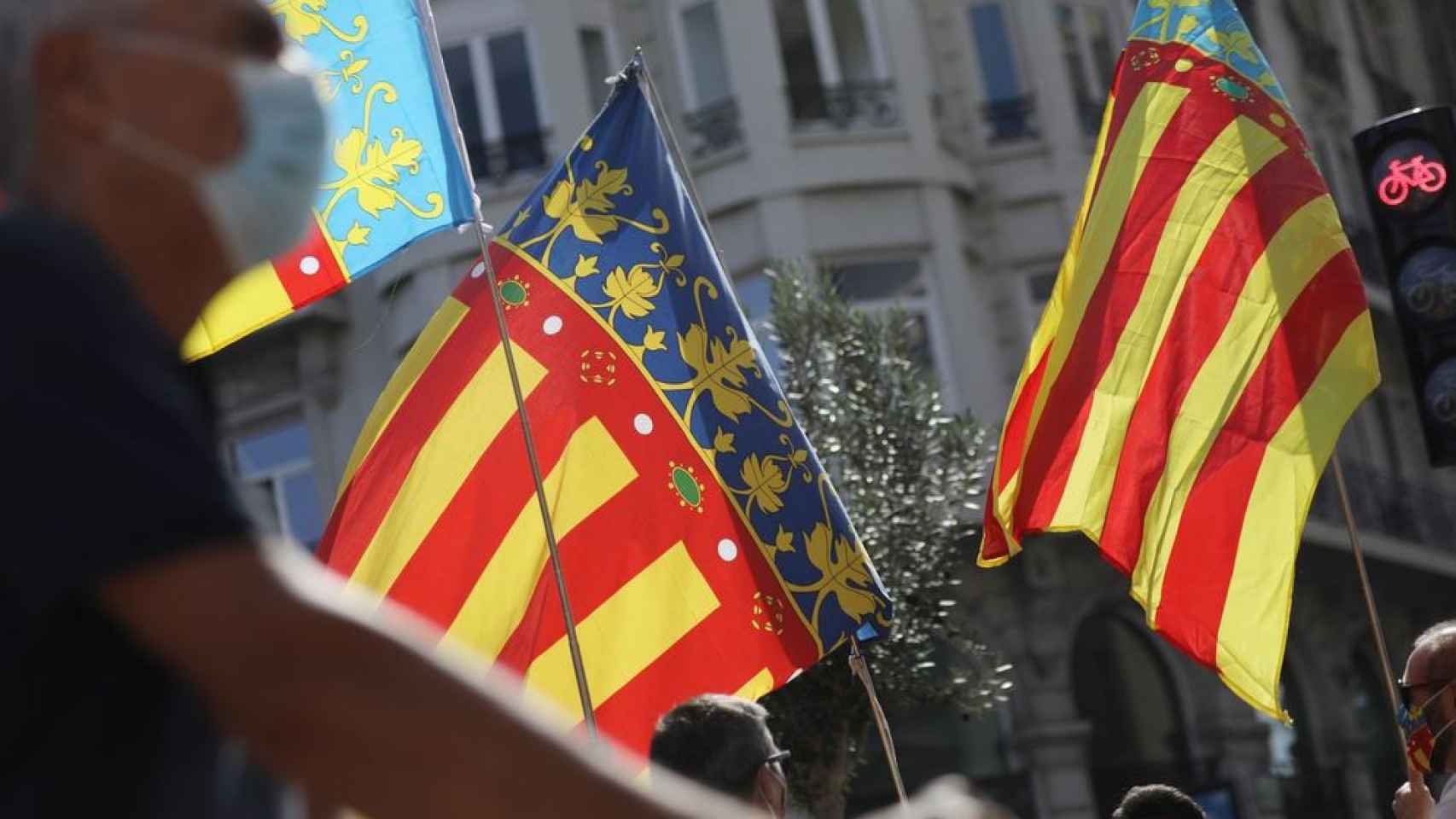 Varias personas ondean la bandera valenciana en un acto convocado por el Ayuntamiento.