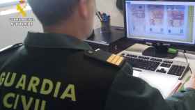 Una agente de la Guardia Civil observando una imagen de los billetes falsos