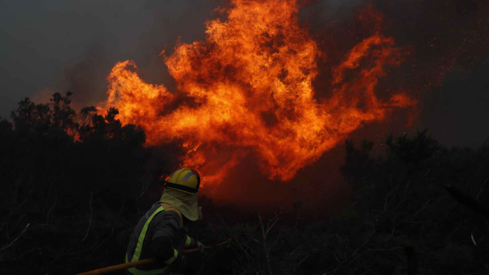 Un bombero intentando apaciguar el fuego en Baleira (Lugo).