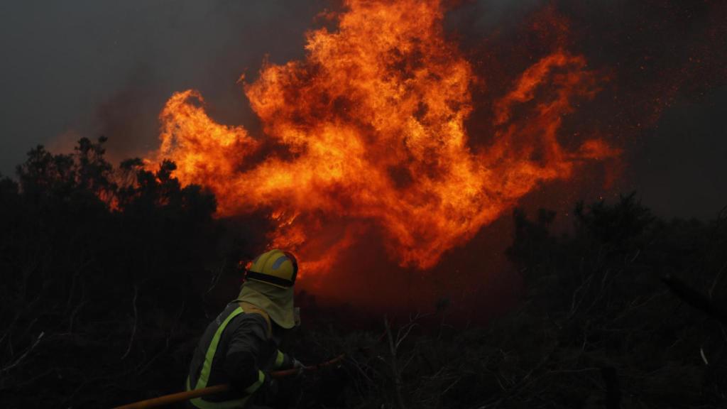 Un bombero intentando apaciguar el fuego en Baleira (Lugo).