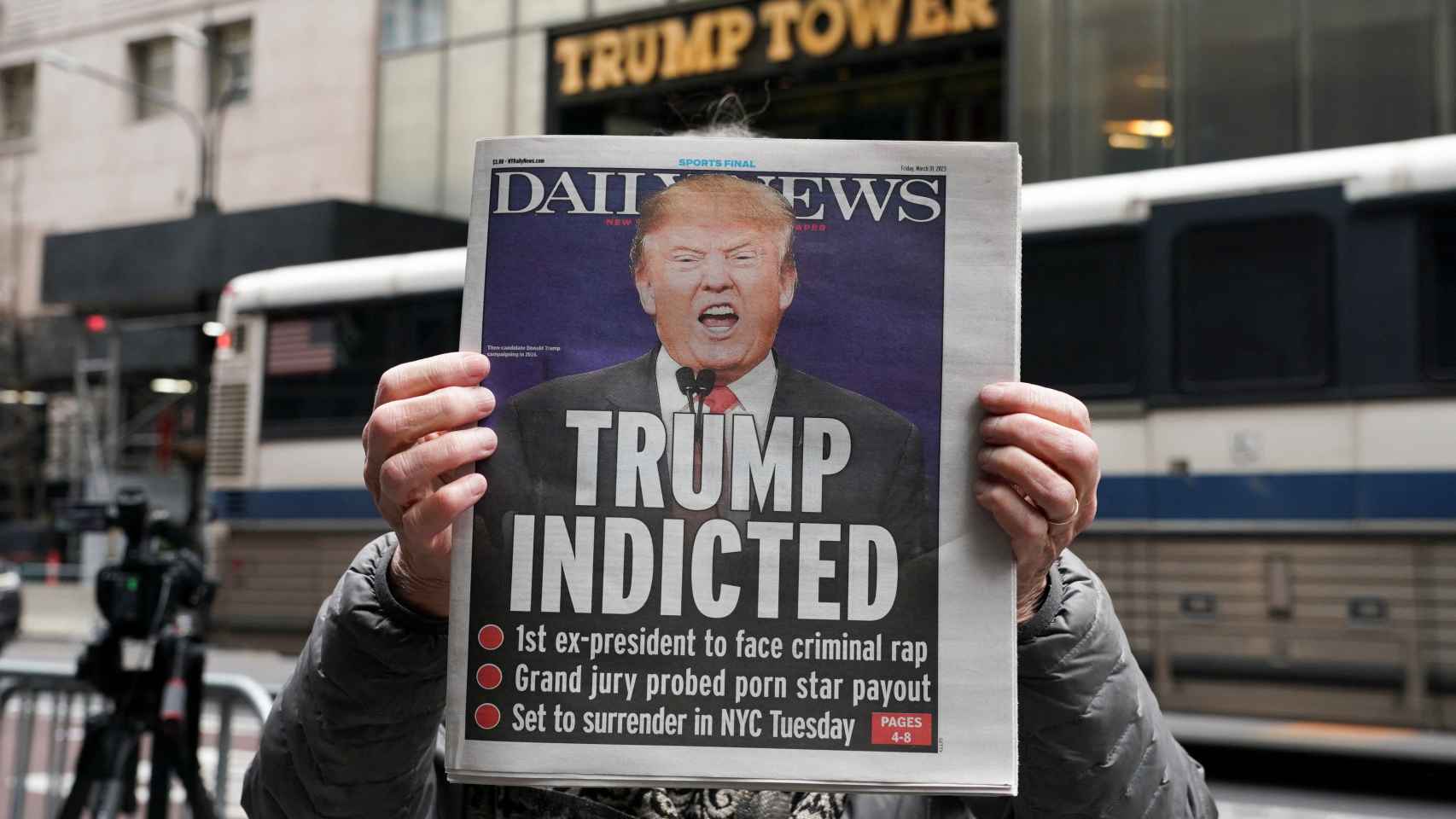 Un estadounidense sostiene frente a la Torre Trump un periódico con la noticia de la imputación del expresidente de EEUU.