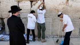 Varias personas retiran las notas del Muro de las Lamentaciones en Jerusalén.