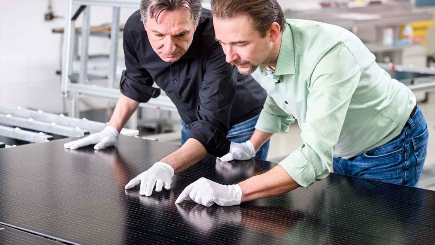 Dos trabajadores de la empresa con el módulo solar.