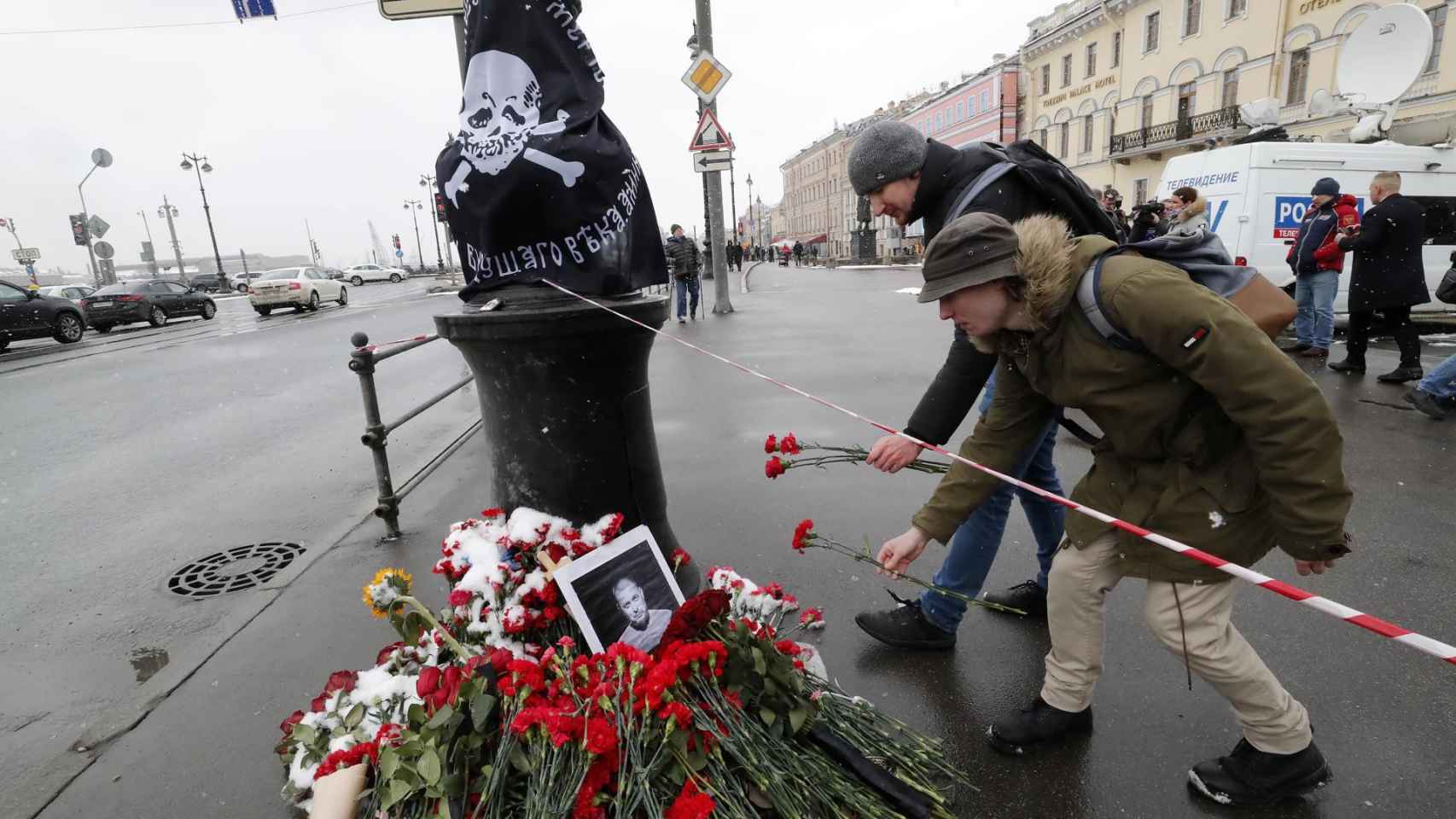 Varios hombres depositan flores en un monumento improvisado en memoria del bloguero militar ruso Vladlen Tatarsky.