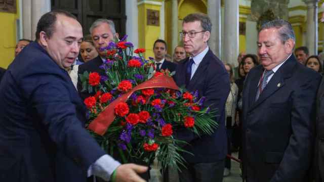 El presidente del PP, Alberto Núñez Feijóo, entrega un ramo de flores a la hermandad de San Benito de Sevilla.