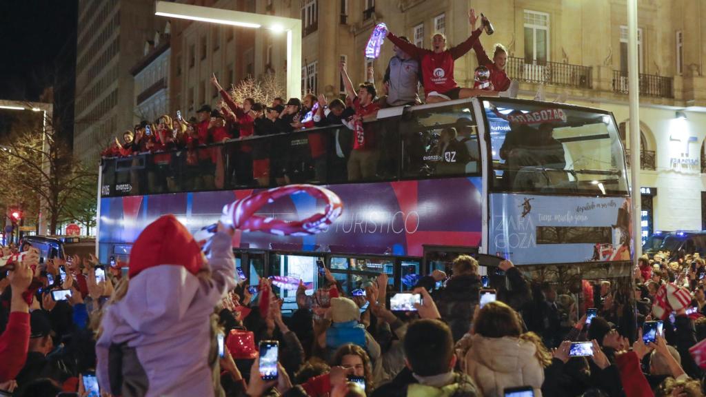 El autobús de Casademont recorriendo las callas con multitud de público a su alrededor.