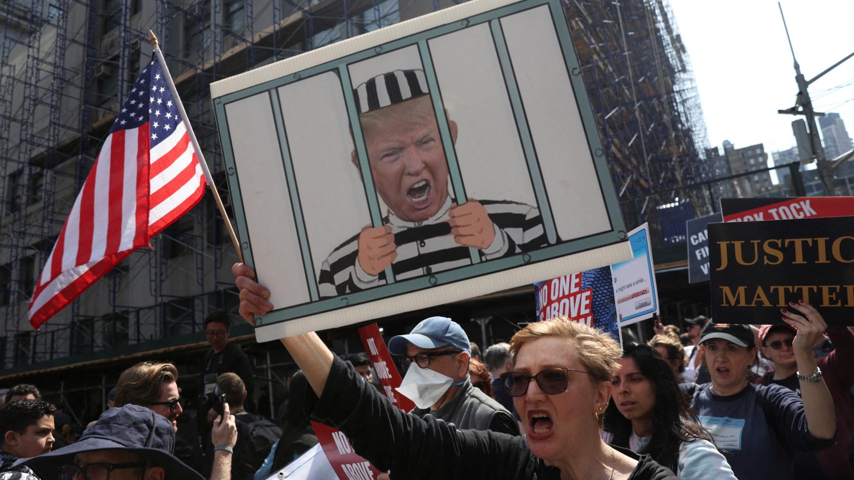 Un grupo de personas se manifiesta frente al Tribunal Penal de Manhattan antes de la lectura de cargos a Donald Trump.