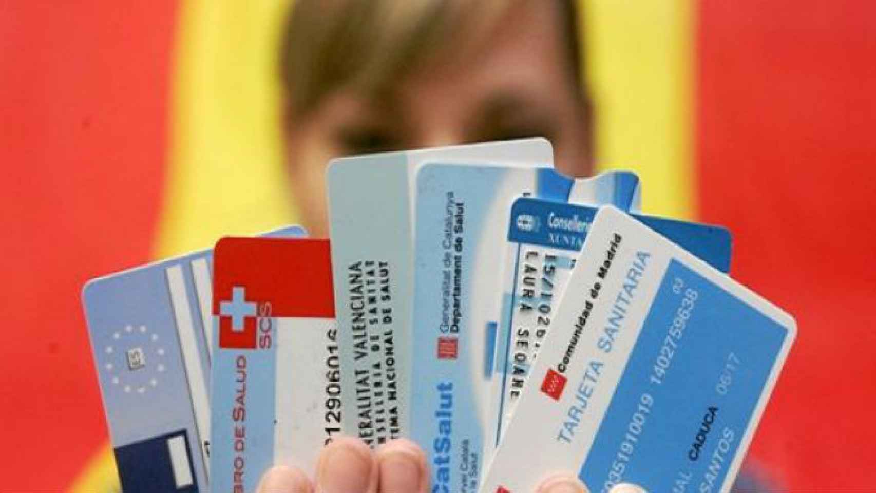 Una mujer sujeta varias tarjetas sanitarias de distintas comunidades autónomas.