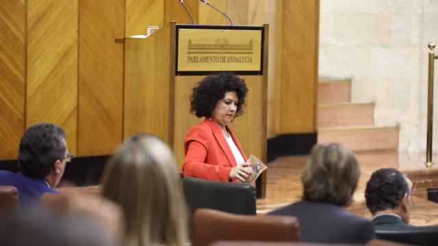 La diputada de Adelante Andalucía Maribel Mora echa un jarro de arena en el escaño del presidente de la Junta, Juanma Moreno, ausente en el pleno.