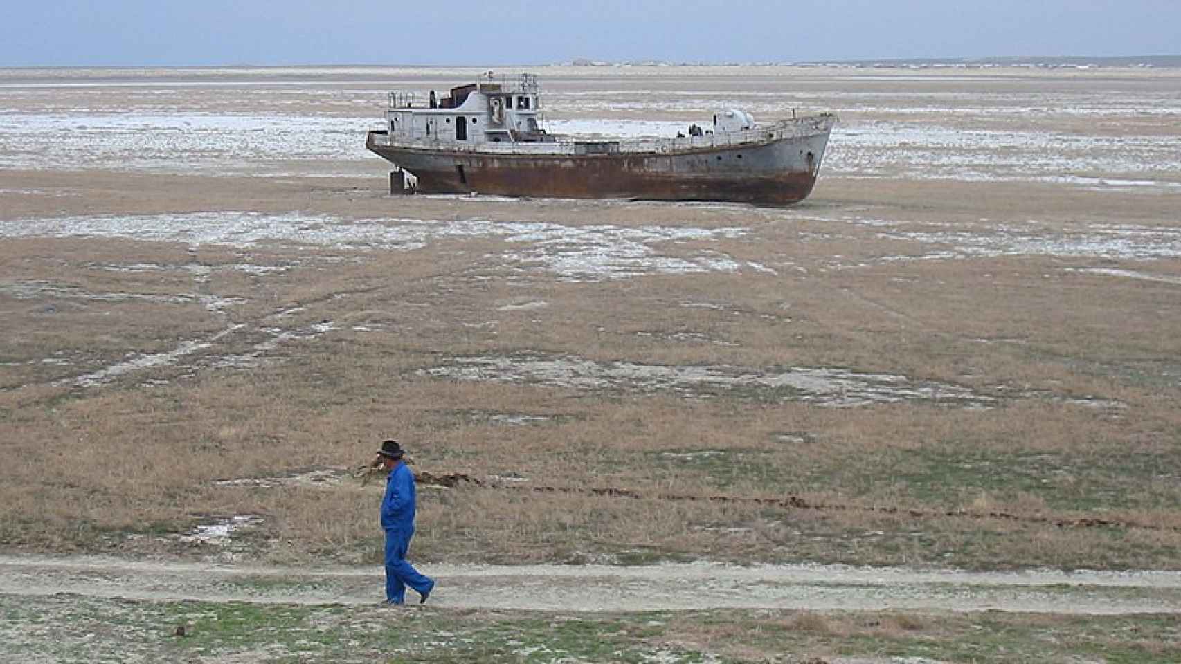 Una persona pasa junto a un barco encallado en el mar de Aral.