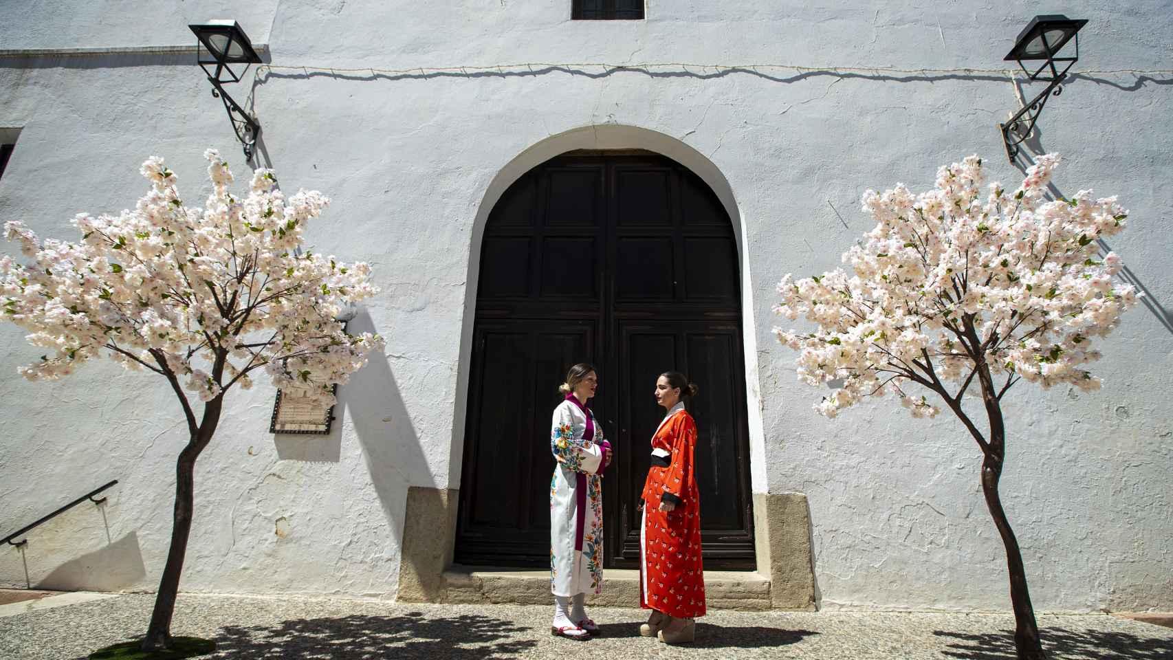 Unas vecinas de Alfarnate vestidas con kimonos ante unos cerezos realizado con flores de papel.