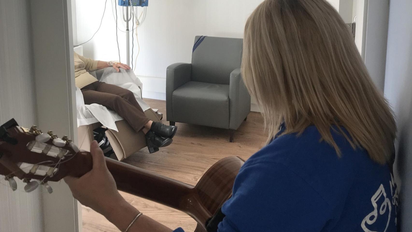 Una mujer tocando la guitarra en un hospital.