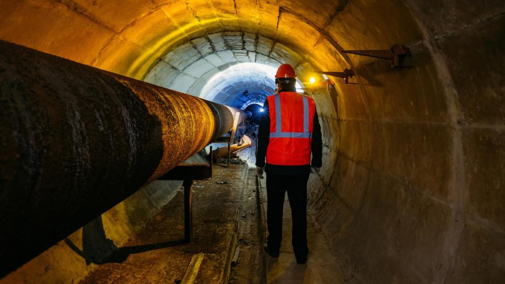 Un trabajador junto a una tubería de suministro de agua