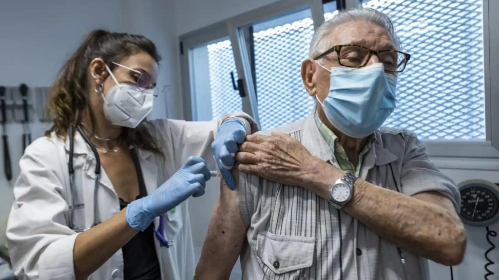 Una sanitaria inyectando la vacuna contra la gripe a una persona mayor.