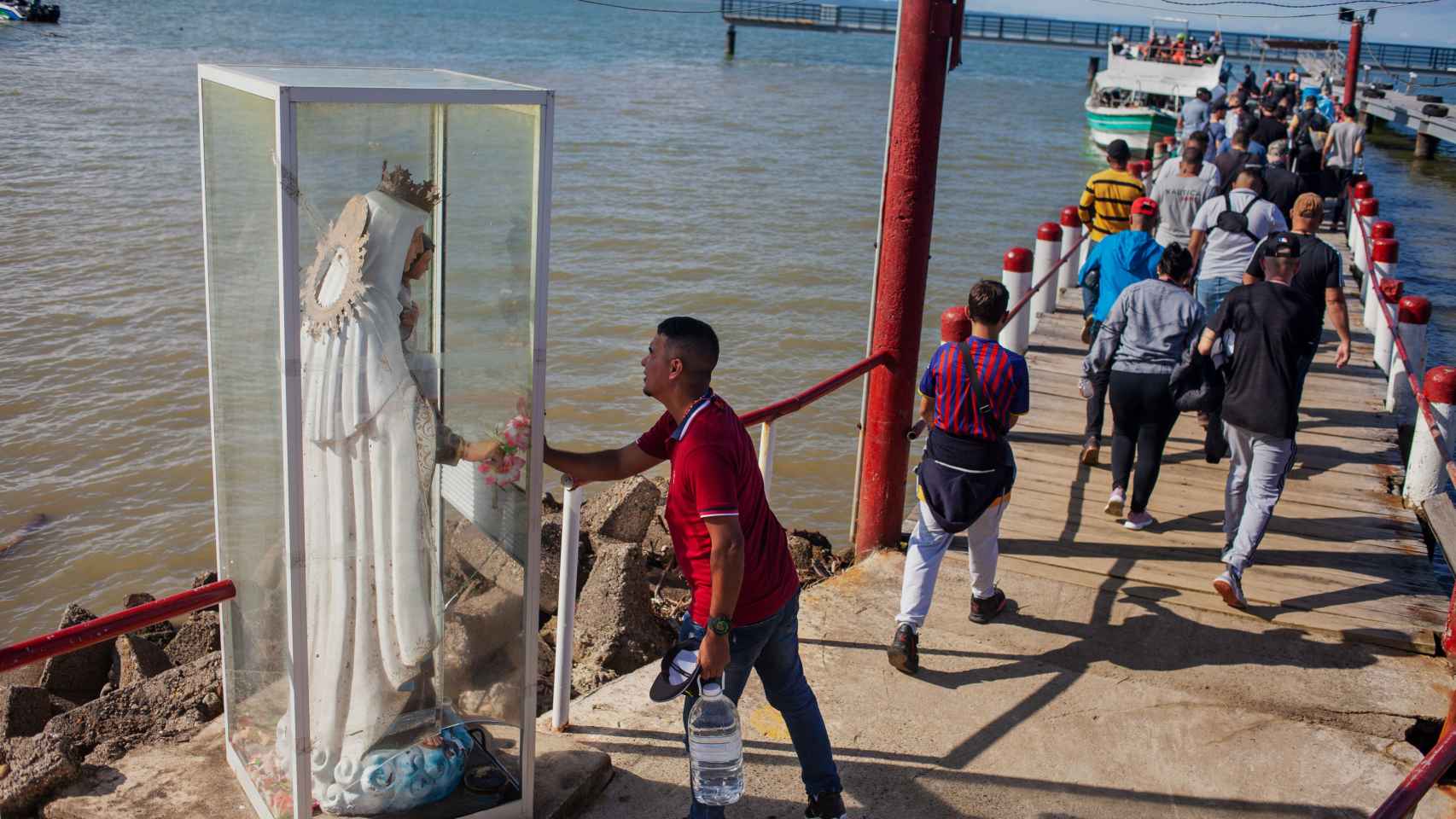 Un grupo de migrantes embarca en el puerto colombiano de Necoclí amparado por una virgen.