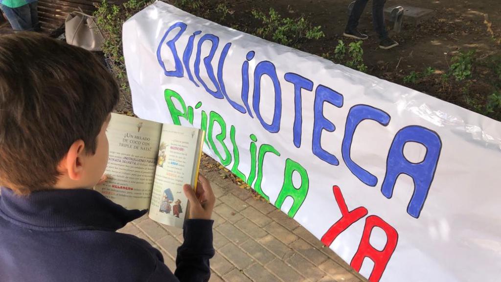 Un niño lee un libro en el acto de protesta en Parque Litoral para reclamar una biblioteca pública.