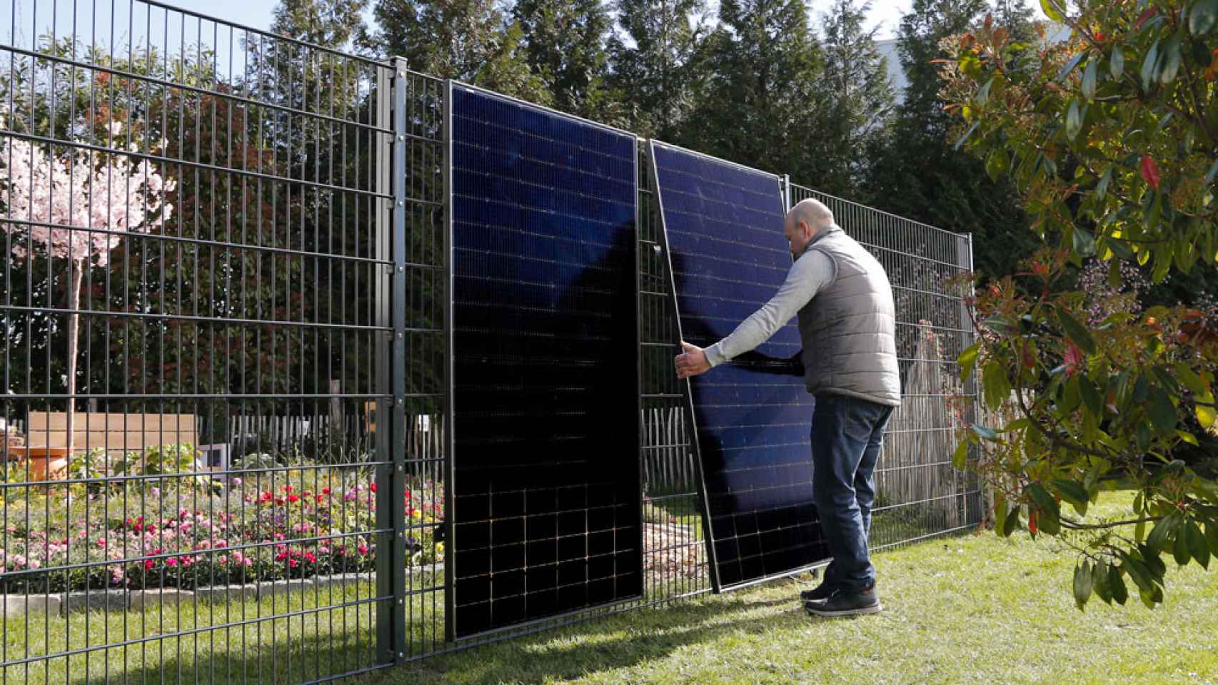 Un usuario instalando placas solares en vertical en una valla