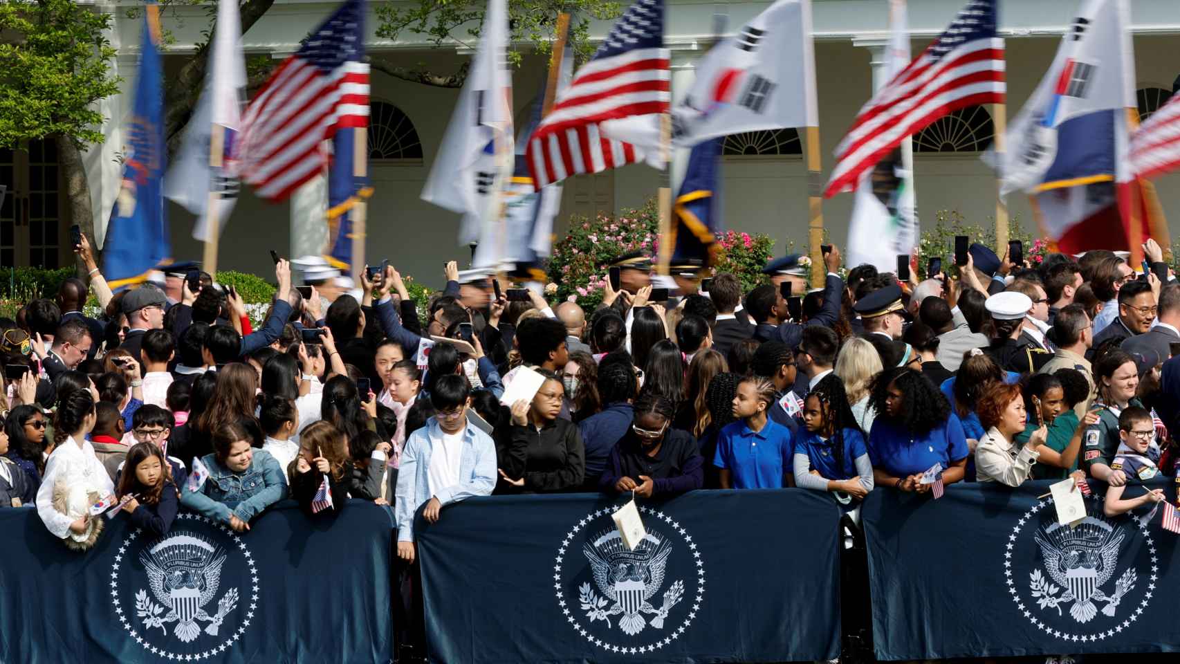 La gente espera con banderas la llegada de Yoon Suk-yeol en el jardín sur de la Casa Blanca, este miércoles.