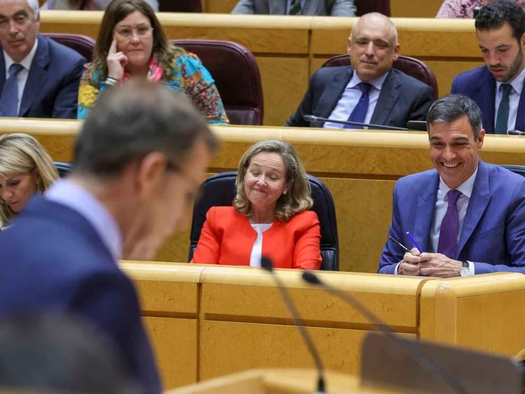 Nadia Calviño y Pedro Sánchez ríen durante la intervención de Feijóo en el Senado.